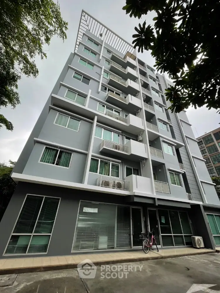 Modern multi-story apartment building with balconies and large windows in urban setting.