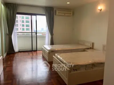 Spacious bedroom with twin beds and balcony access in modern apartment