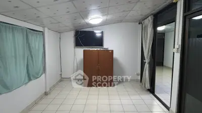 Spacious room with tiled floor, TV, and wardrobe, ideal for versatile living arrangements.