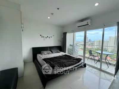 Modern bedroom with balcony offering stunning city views, featuring sleek furnishings and abundant natural light.