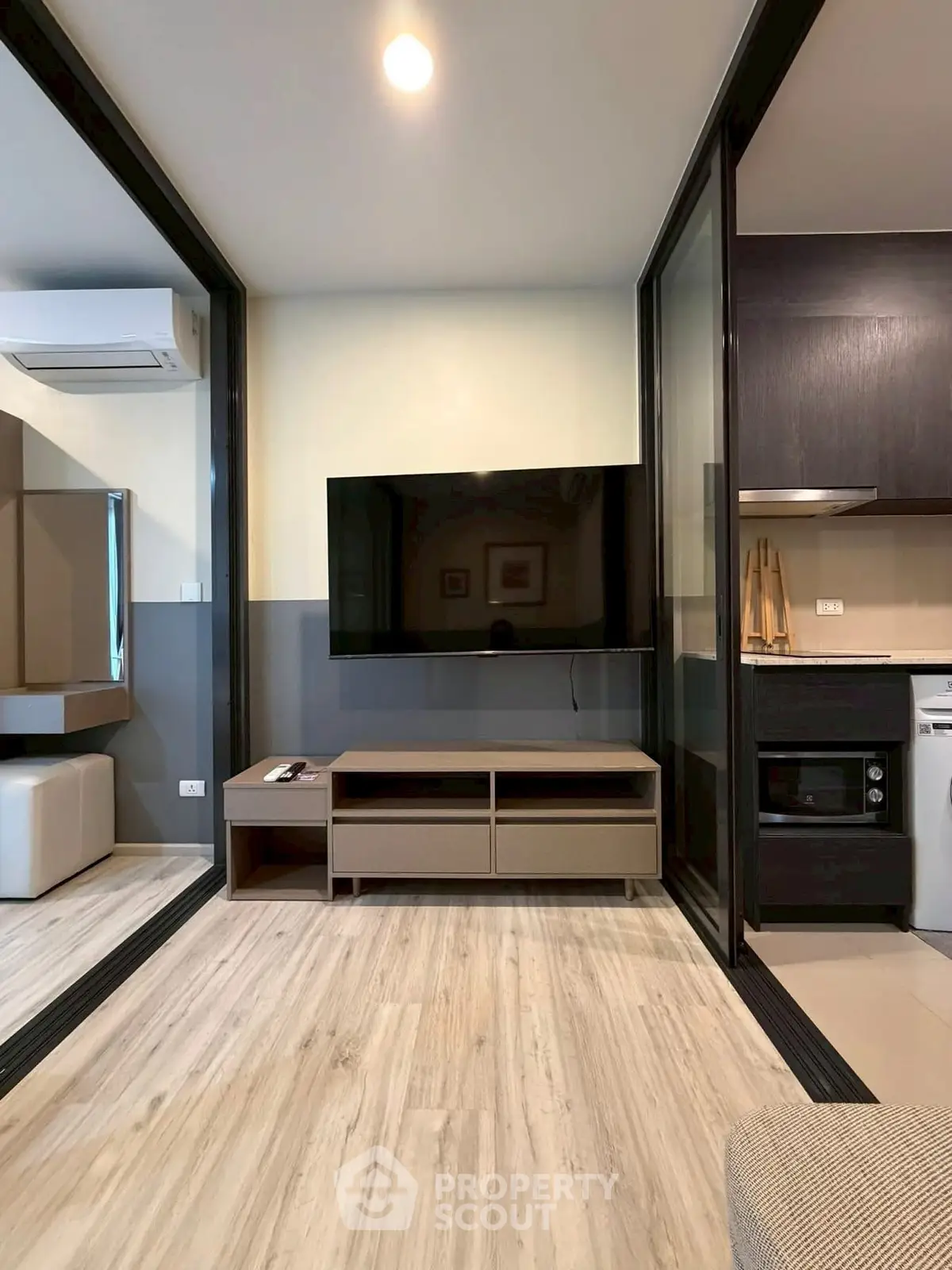 Modern living room with sleek TV setup and open kitchen layout in stylish apartment.