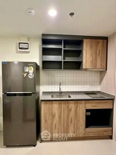 Modern kitchen with sleek cabinetry and stainless steel fridge in a stylish apartment.