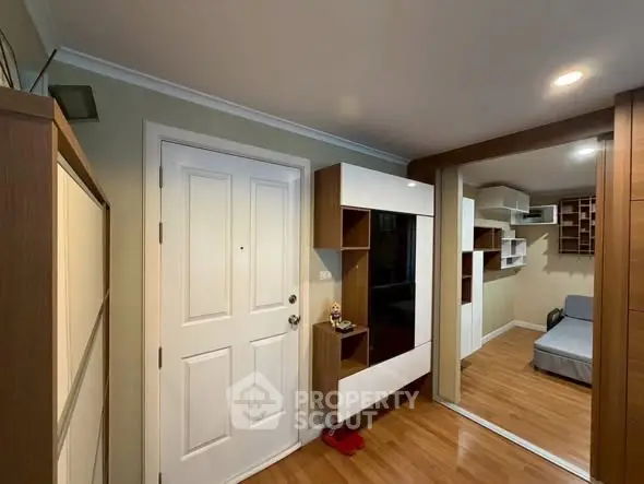 Modern apartment entrance with stylish wooden flooring and built-in storage solutions.