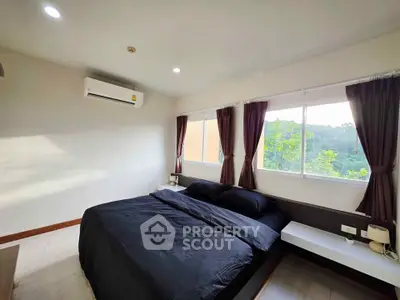 Spacious bedroom with large windows and scenic view, featuring modern decor and ample natural light.