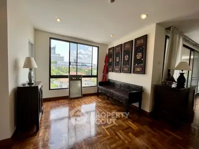 Elegant living room with parquet flooring and city view, featuring traditional decor and ample natural light.