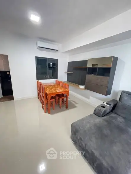 Modern living room with sleek furniture and dining area, featuring a cozy ambiance.