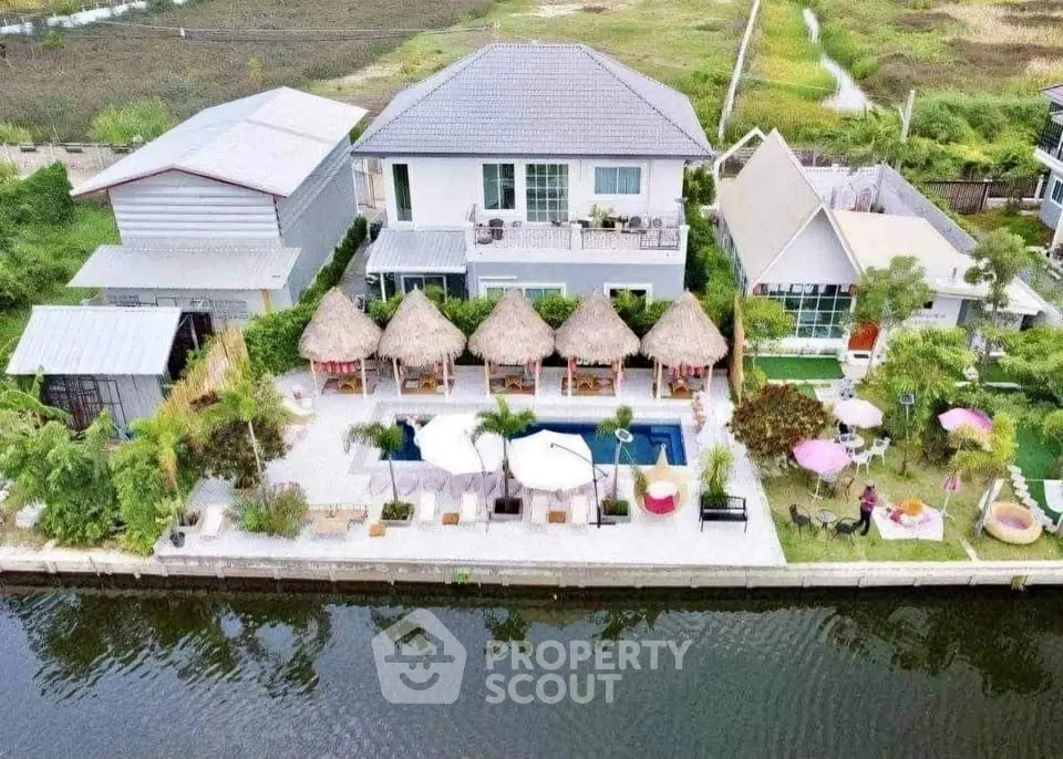 Stunning waterfront property with pool and thatched cabanas, perfect for luxury living and entertaining.