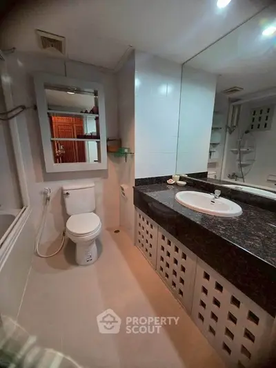 Modern bathroom with sleek fixtures and large mirror, featuring a bathtub and stylish vanity.