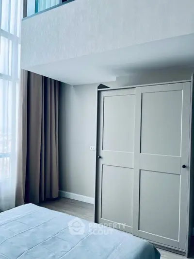 Modern bedroom with high ceiling and large wardrobe in stylish apartment