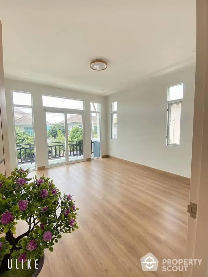 Spacious living room with abundant natural light, elegant wood flooring, and direct balcony access, perfect for entertaining and relaxation.