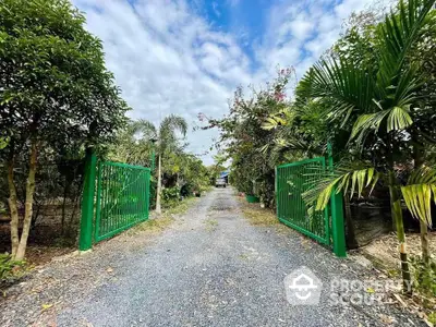 Charming gated entrance with lush greenery and gravel driveway