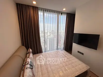 Modern bedroom with city view, featuring a wall-mounted TV and floor-to-ceiling windows.