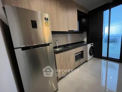 Modern kitchen with stainless steel fridge and washing machine, sleek cabinetry, and large window view.