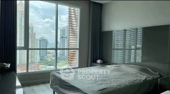 Spacious bedroom with stunning city view through large windows in modern apartment.