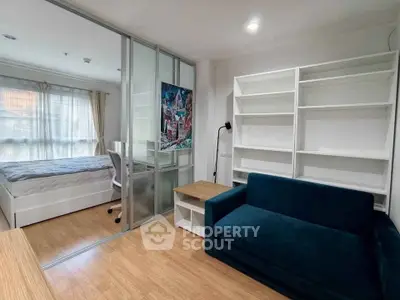 Modern studio apartment with cozy living area and bedroom separated by glass partition.