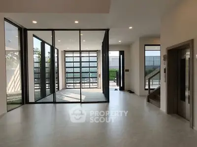 Spacious modern living room with large windows and elevator access, perfect for natural light lovers.