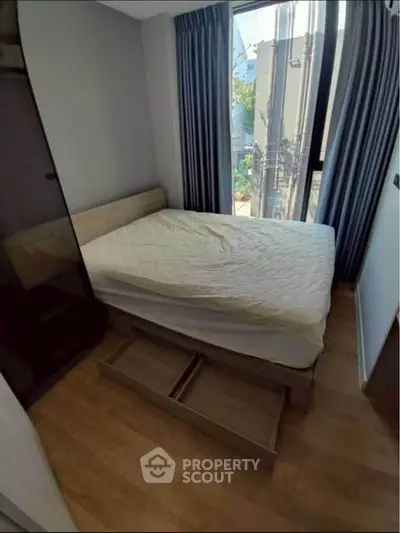 Cozy bedroom with wooden flooring and large window for natural light.