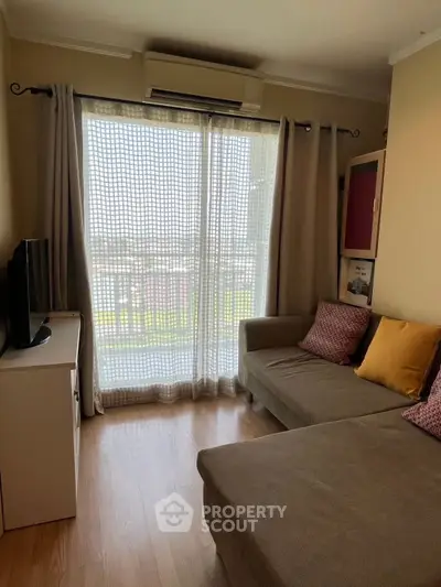 Cozy living room with large sofa and natural light from balcony window.