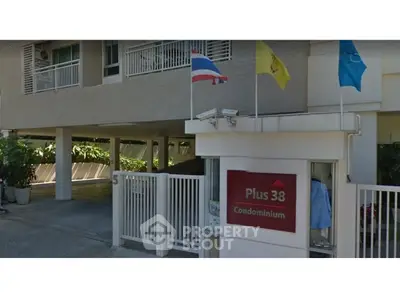 Modern condominium entrance with flags and secure gated access in urban setting.
