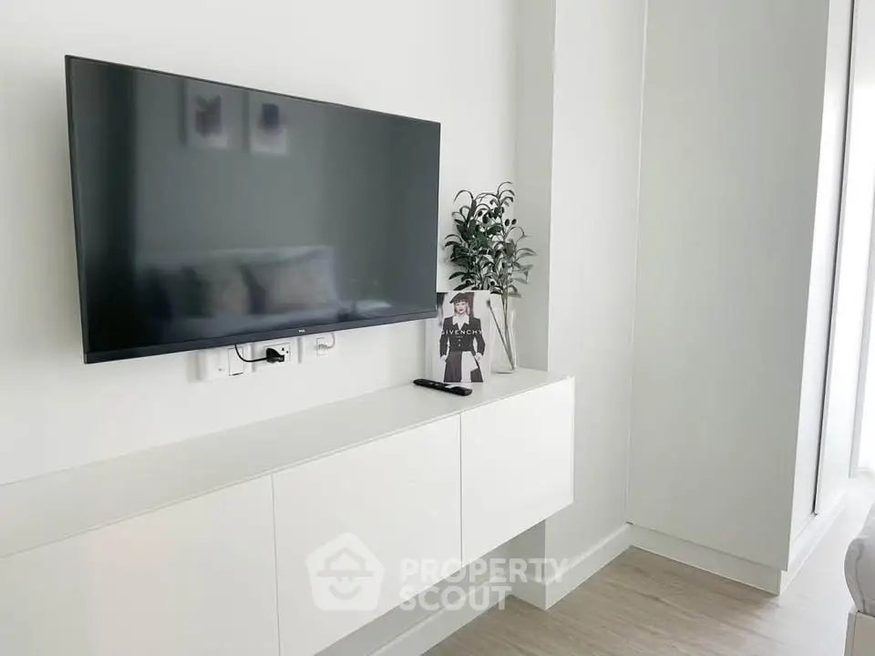 Modern living room with wall-mounted TV and sleek white cabinetry