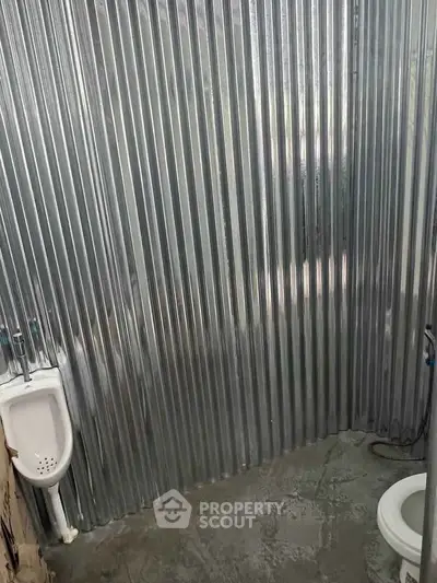 Industrial-style bathroom with corrugated metal walls and concrete floor