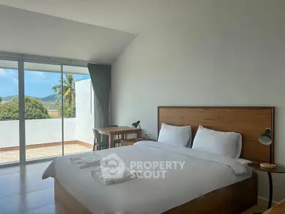 Spacious bedroom with modern decor and large window offering scenic views