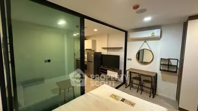 Modern studio apartment with glass partition, sleek furniture, and air conditioning.