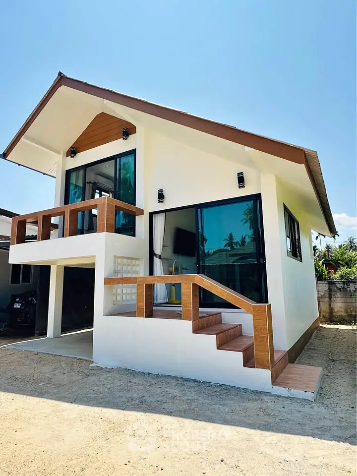 Charming modern two-story house with large windows and a stylish balcony, perfect for tropical living.