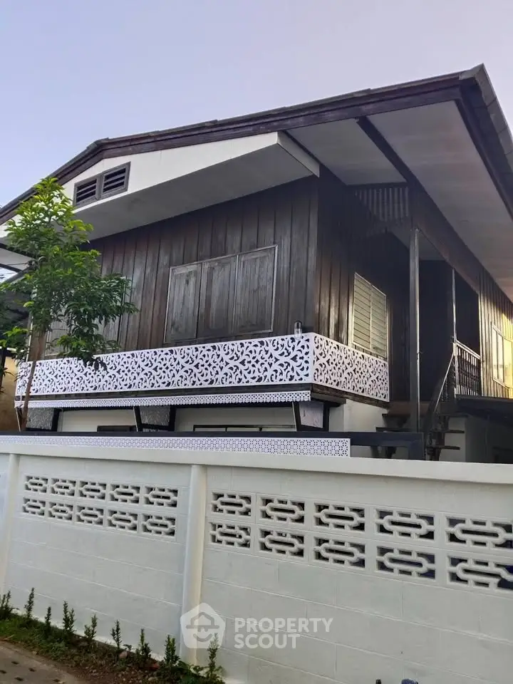 Charming traditional wooden house with intricate balcony design and lush greenery.