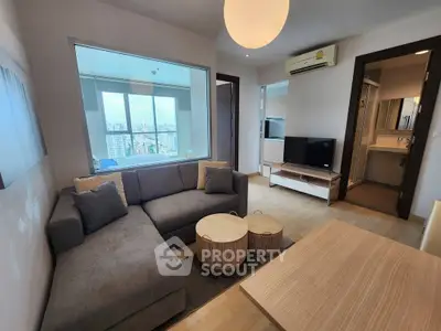 Modern living room with city view, cozy sofa, and stylish decor in a high-rise apartment.