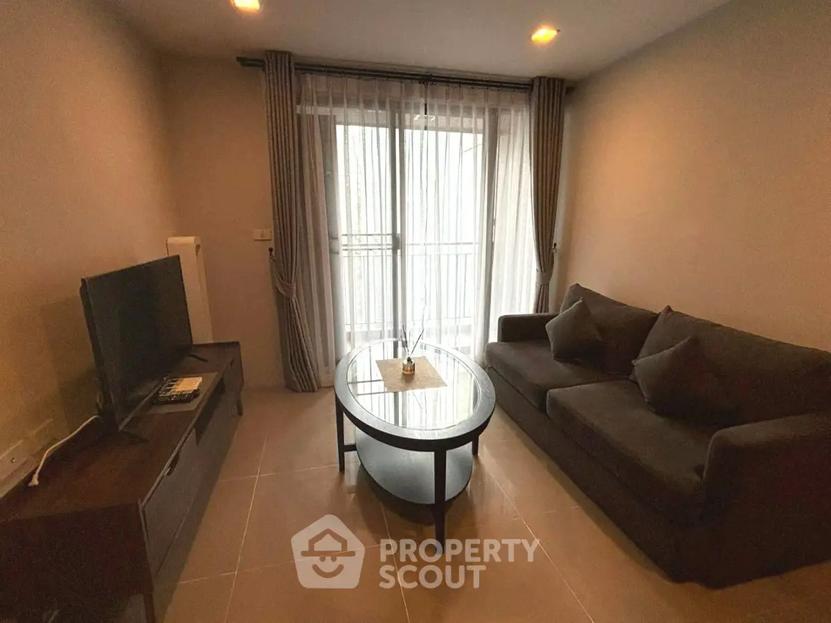 Cozy living room with modern furniture and natural light from large window.