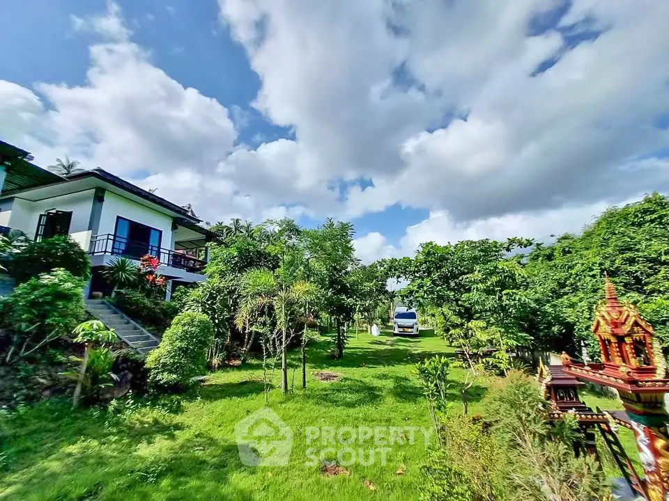 Charming house with lush garden and vibrant greenery under a bright blue sky.