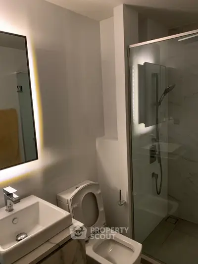 Modern bathroom with sleek fixtures and glass shower enclosure in contemporary apartment.