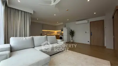 Modern open-plan living room with cozy sofa and stylish kitchen in a contemporary apartment.