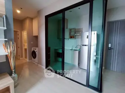 Modern apartment with sleek kitchen and washing machine, featuring glass sliding doors.