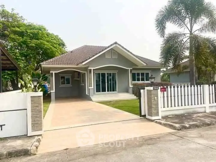 Charming single-story home with driveway and lush greenery in a serene neighborhood.