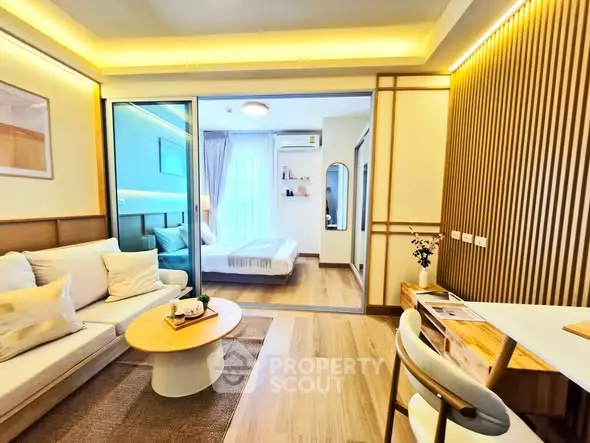 Modern open-plan living room with cozy bedroom view, stylish decor, and warm lighting.