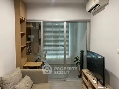 Modern living room with cozy sofa, TV, and study area with natural light.