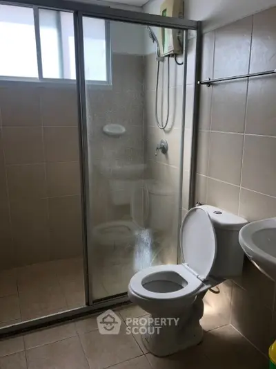 Modern bathroom with glass shower and tiled walls, featuring a sleek design.