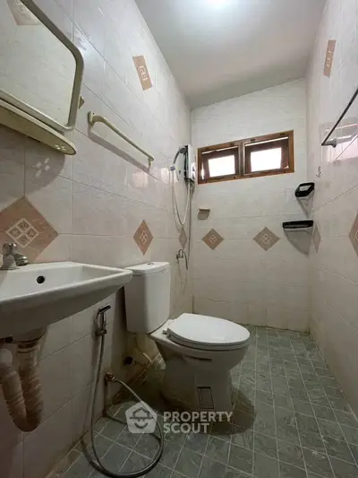 Compact bathroom with modern fixtures and tiled walls, featuring a shower and toilet.