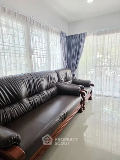 Spacious living room with elegant leather sofa and large windows for natural light.