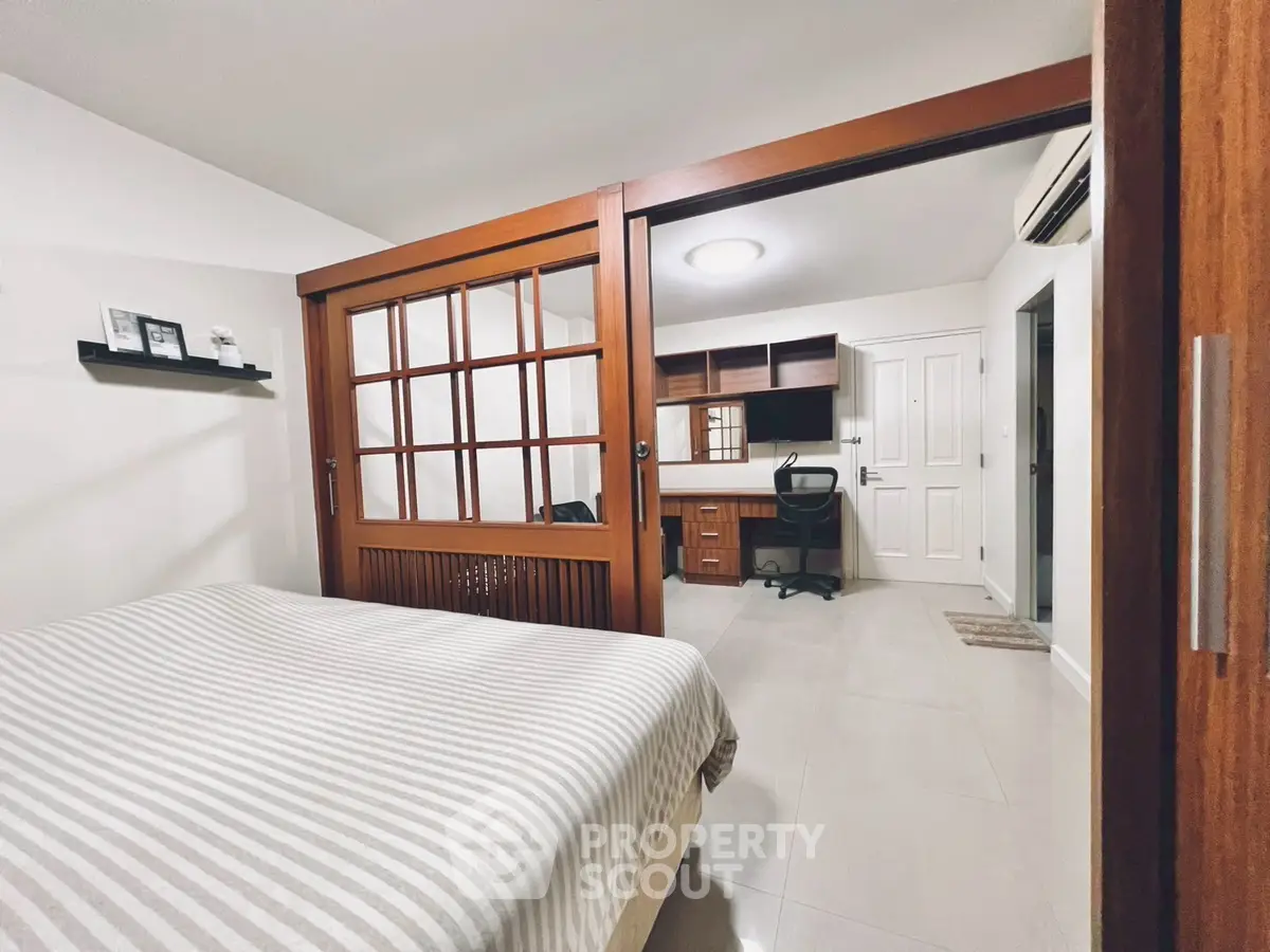Modern bedroom with sliding wooden doors leading to a stylish study area.