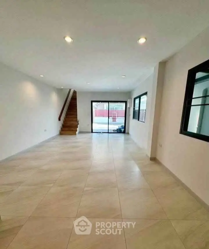 Spacious open-plan living room with modern tile flooring and large windows for natural light.