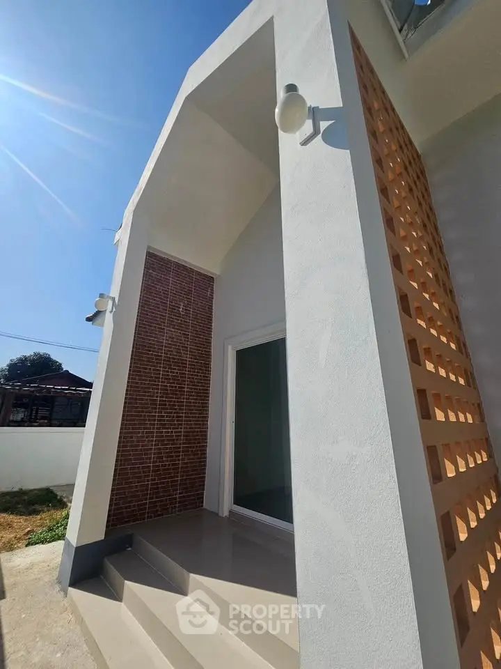 Modern architectural entrance with unique brick lattice design and sleek white facade.