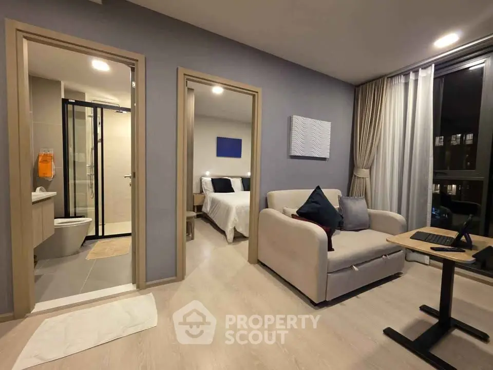 Modern apartment interior with cozy living room and adjacent bedroom, featuring stylish decor and ample natural light.