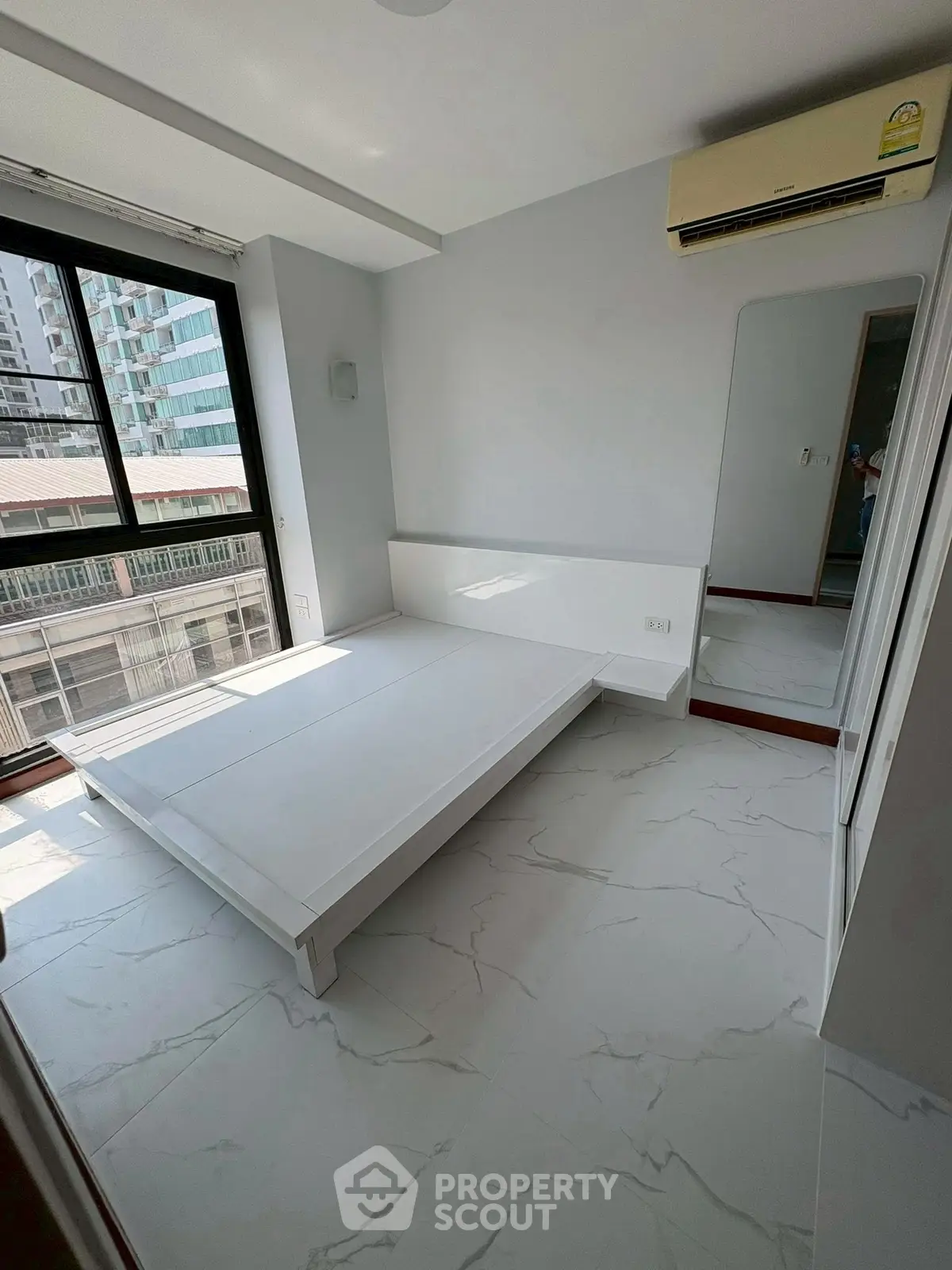 Modern minimalist bedroom with large window and air conditioning in urban apartment