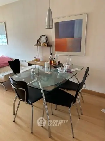 Modern dining area with glass table and contemporary art in stylish apartment.