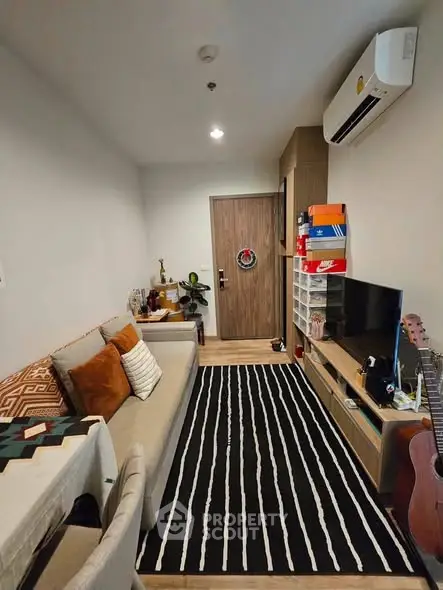 Cozy living room with modern decor and air conditioning, featuring a stylish black and white rug.