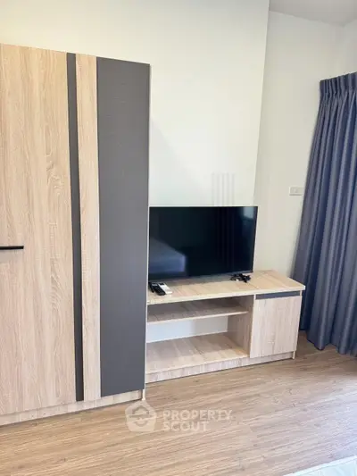 Modern living room with stylish wooden furniture and flat-screen TV, perfect for cozy entertainment.