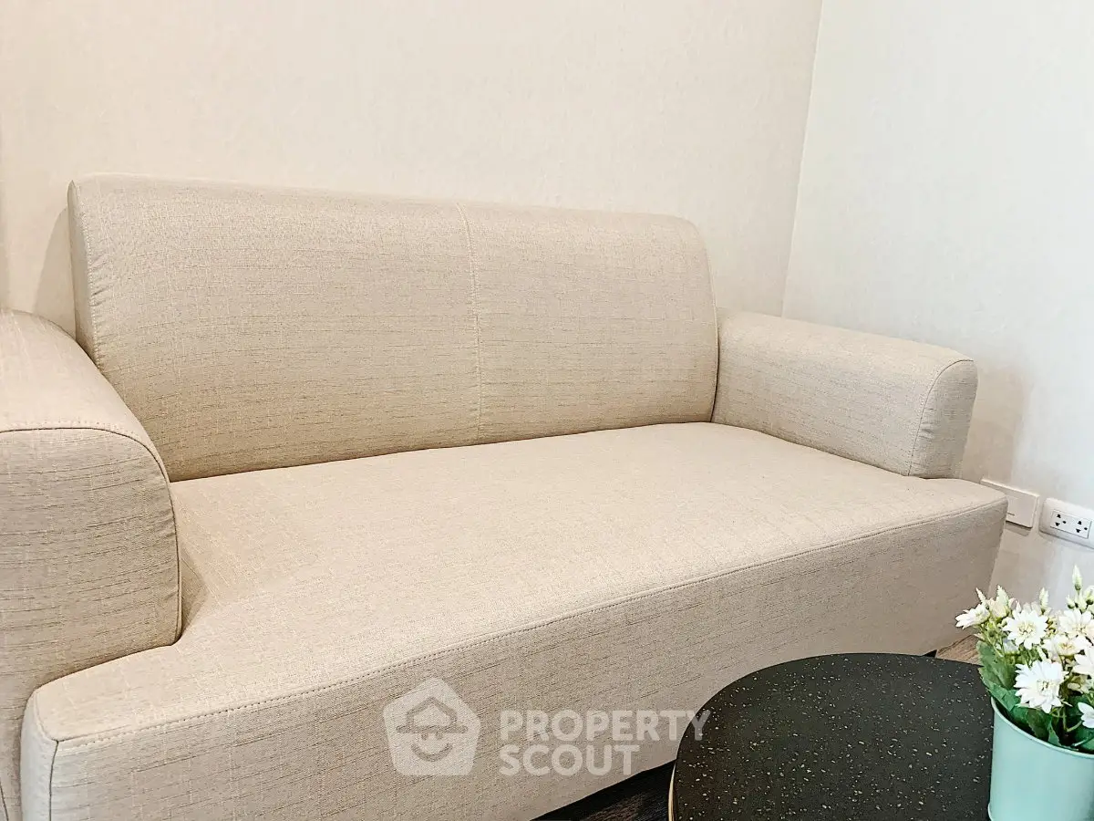 Cozy beige sofa in a modern living room setting with a stylish coffee table and decorative plant.